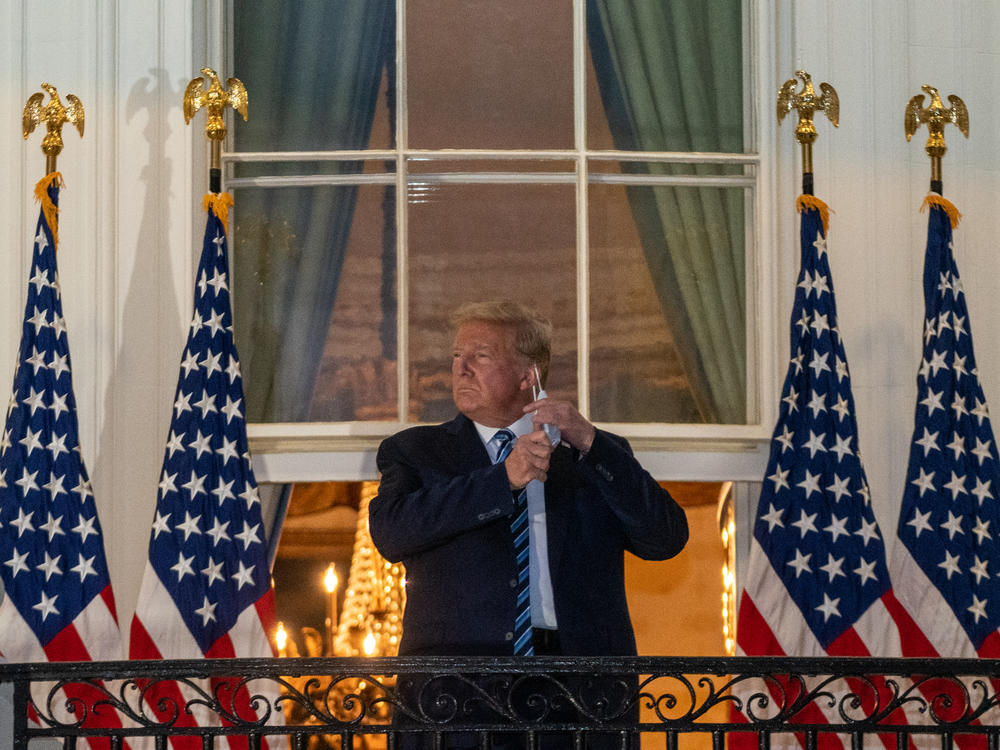 According to one new account of the Trump presidency, even telling the story of Donald Trump's COVID-19 diagnosis was difficult due to the chaos in the White House. Here, Trump removes his mask after being discharged from the Walter Reed National Military Medical Center in October.