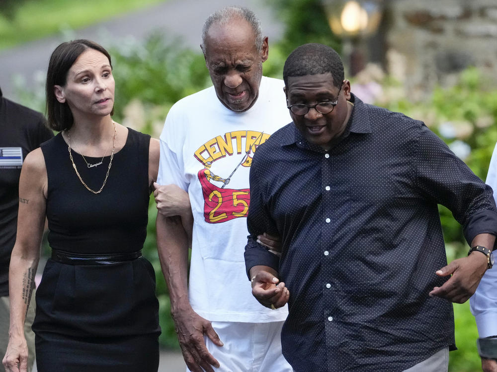 Bill Cosby (center) approaches members of the media gathered outside his home in Cheltenham, Pa., with his spokesperson Andrew Wyatt. On Wednesday, Pennsylvania's highest court overturned Cosby's sex assault conviction, and he was released from prison.