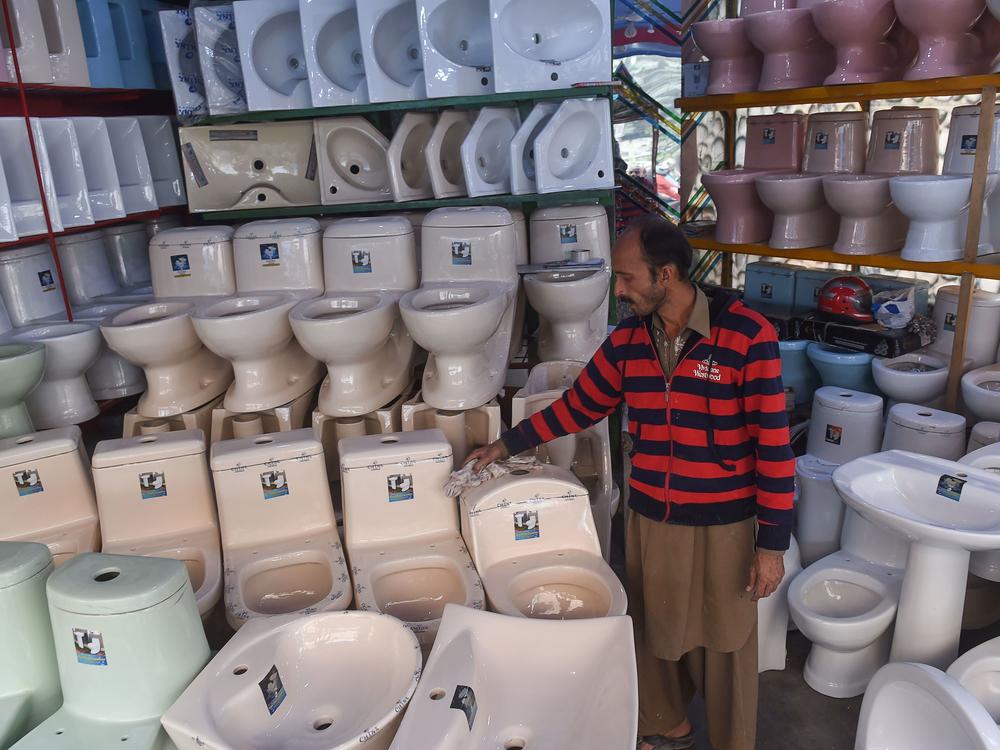 A Pakistani shopkeeper cleans toilets on display inside his shop in Lahore.