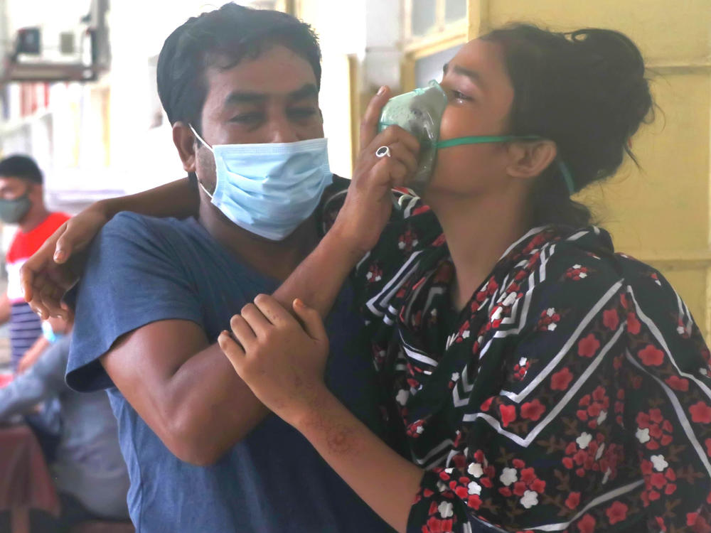 A man assists a patient with difficulty breathing at the Medical College Hospital in Rajshahi, Bangladesh, on June 16, as the delta variant of the coronavirus quickly spread.