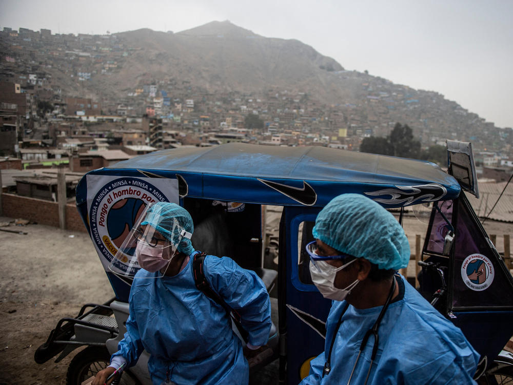 Health workers arrive in a tuk-tuk to administer doses of the Pfizer COVID-19 vaccine to elderly citizens in their homes in Lima, Peru, in April.