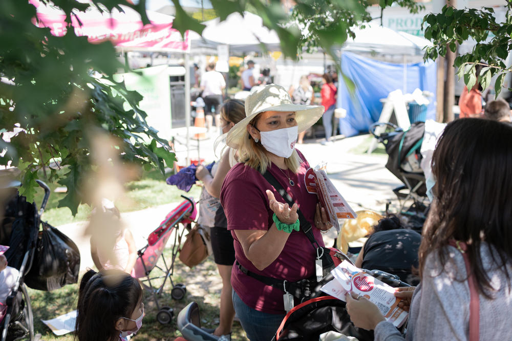 Promotora Ana Parada engages community members at the Crossroads Farmers Market.