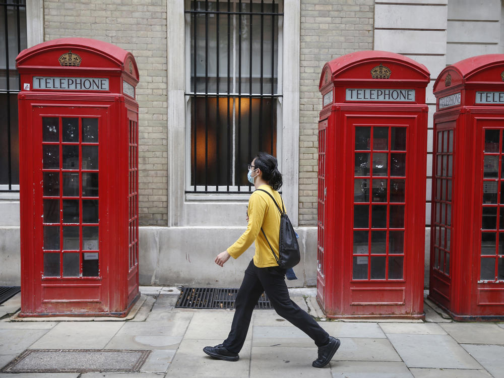 A pedestrian wearing face mask walks past a row of telephone boxes on Sunday in London.