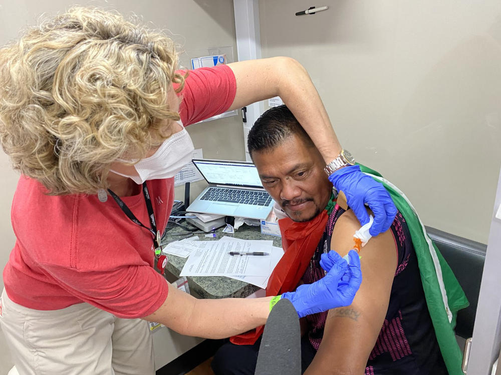 During half-time at a Mexico-USA match in Denver, Oscar Filipe Sanchez receives the Johnson & Johnson COVID-19 vaccination inside a mobile health clinic parked outside Empower Field at Mile High.