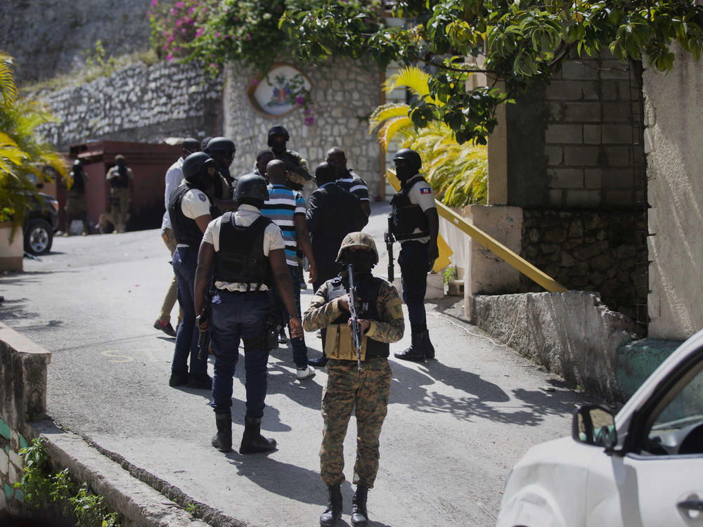 Security forces conduct an investigation as a soldier stands guard at the entrance to the residence of the Haitian president in Port-au-Prince on  Wednesday.