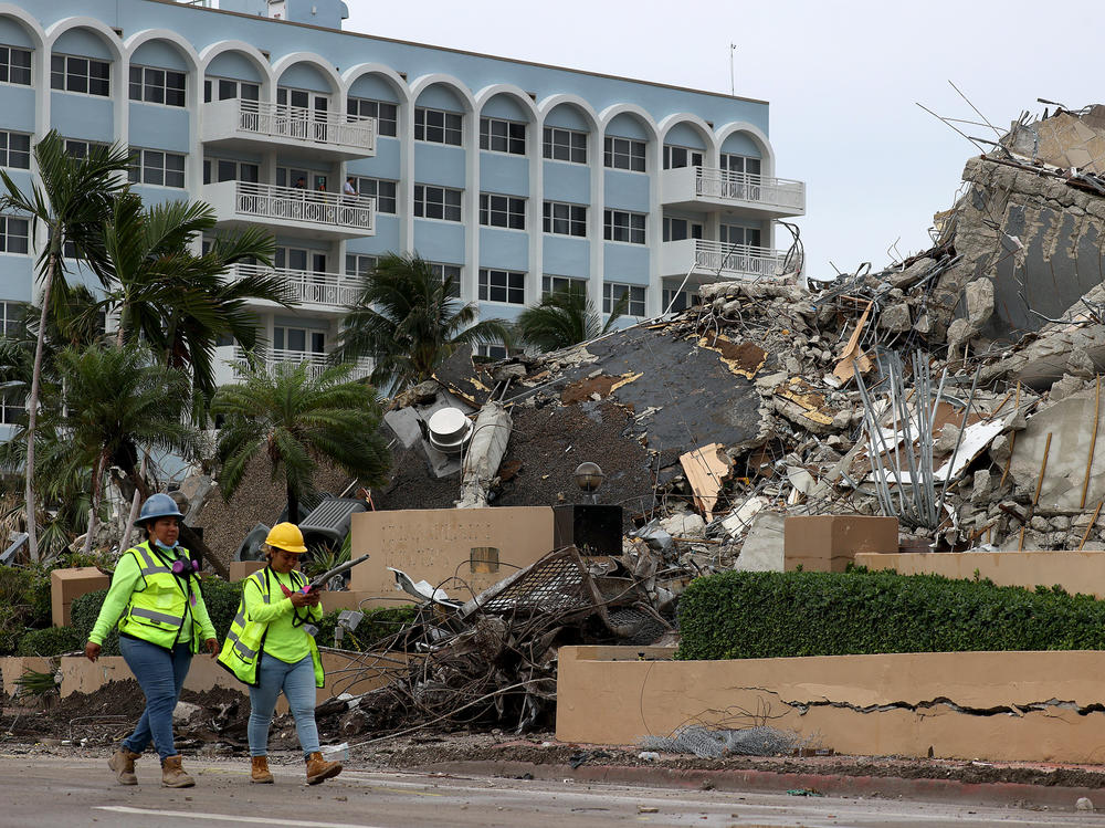 Workers walk past the completely collapsed 12-story condo building Tuesday in Surfside. The portion of the building left standing after the deadly June 24 collapse was demolished Sunday night.