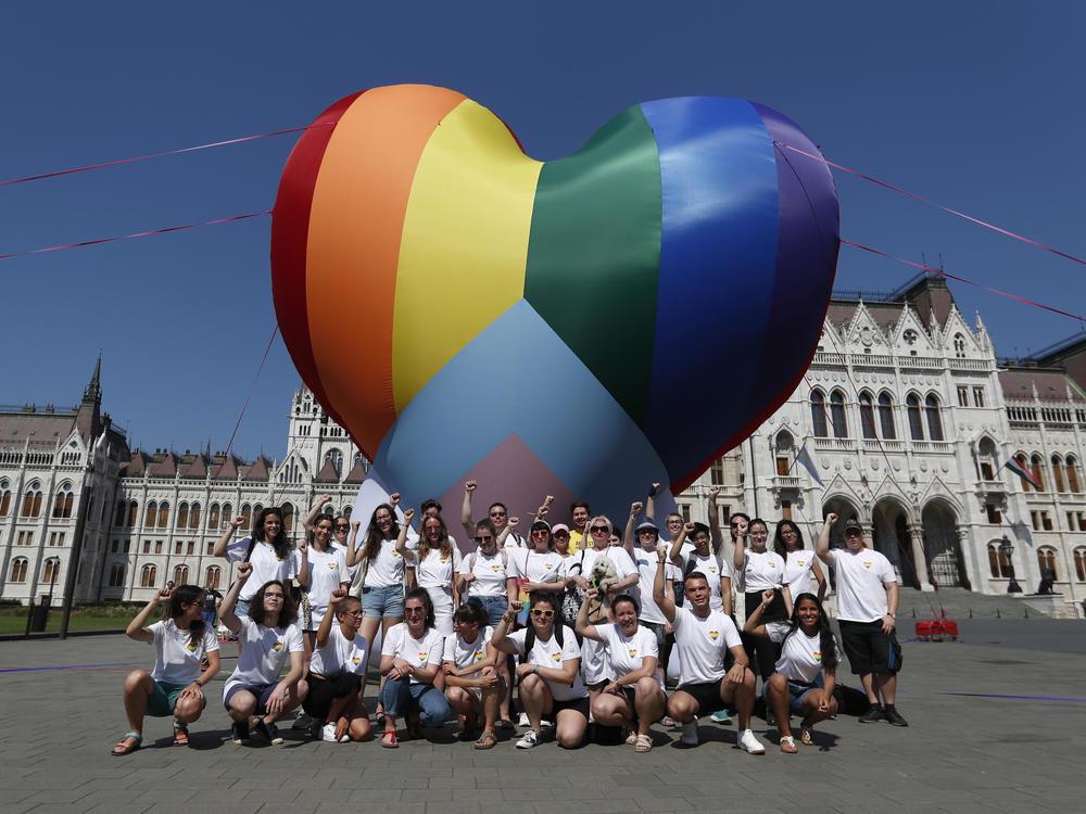 Activists pose for a photo after raising a large rainbow heart in front of Hungary's parliament building in Budapest on Thursday. The activists are protesting against a new law they say discriminates against and marginalizes LGBTQ people.