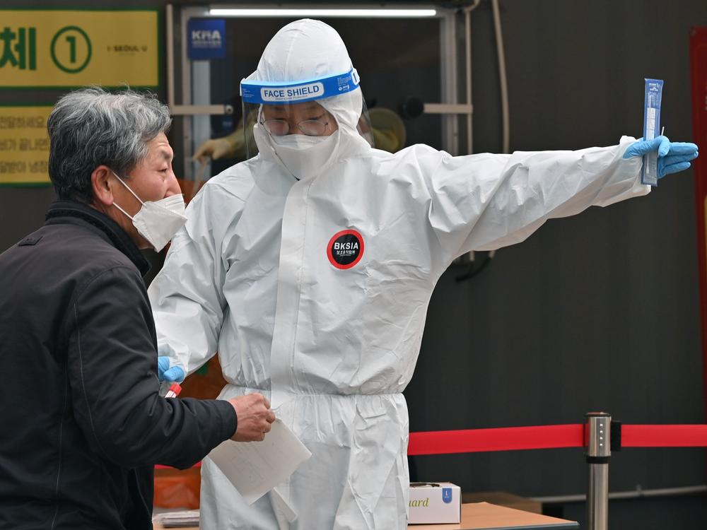 A medical staffer wearing protective gear gestures after collecting a swab from a visitor to test for the coronavirus at a temporary testing station in Seoul in December 2020.  South Korea on Friday announced it would raise restrictions in the capital region to the highest level as a fourth wave of infections is gaining speed.