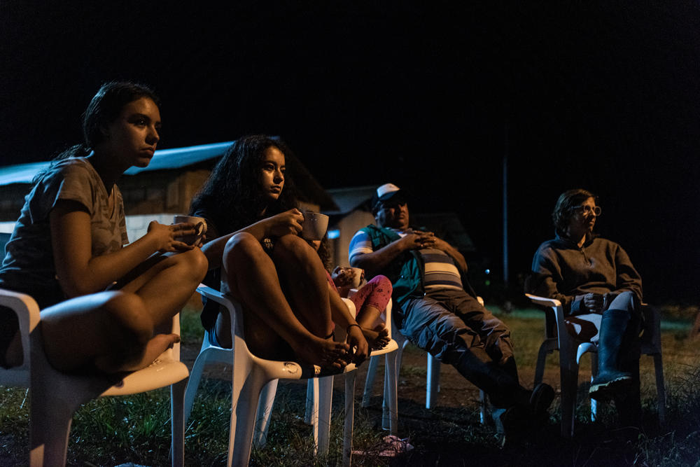 Tourists sit around a campfire at the resettlement camp for former FARC rebels, who told war stories and apologized for the human rights abuses the guerrillas committed during the conflict.