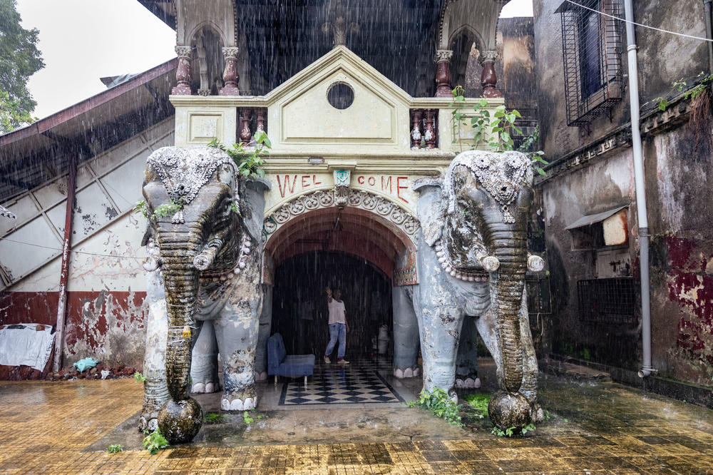 Elephant statues and a security guard stand at one of the entrances of the Imperial Cinema, locked behind heavy metal gates.