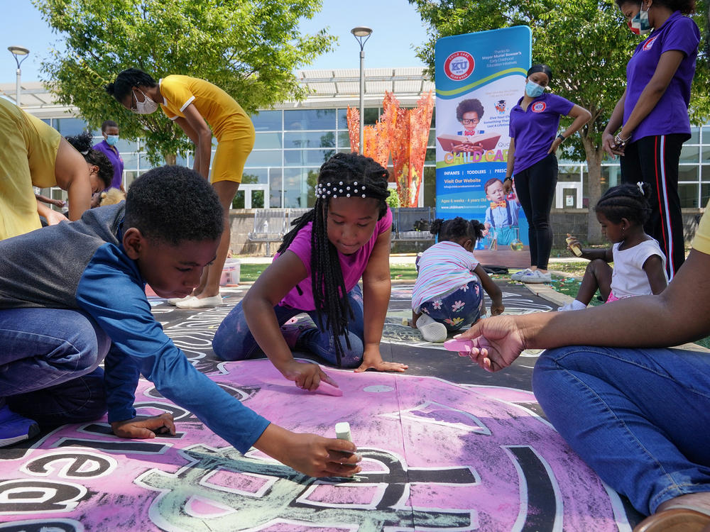 Children and teachers from the KU Kids Deanwood child care center in Washington, D.C., complete a mural in celebration of the launch of the child tax credit.