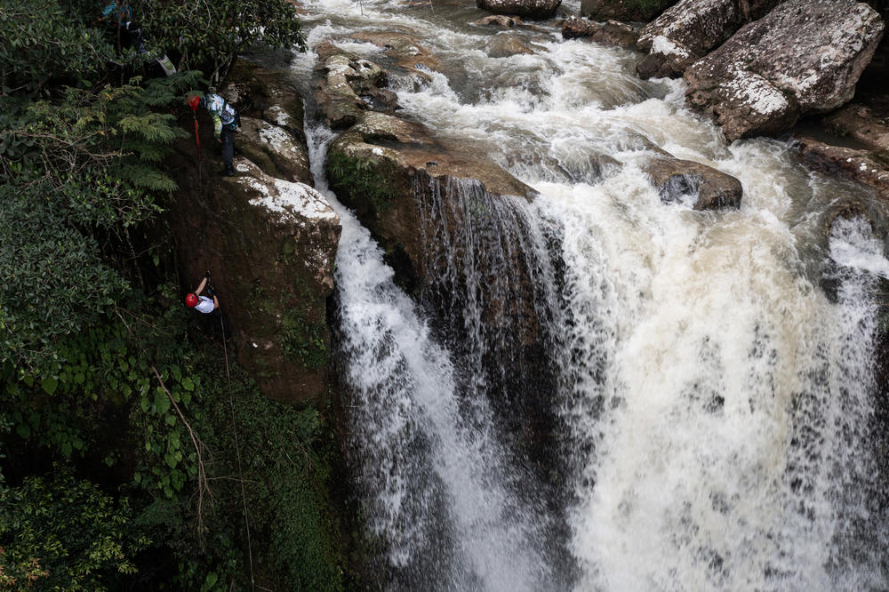 A tourist rappels next to a waterfall.