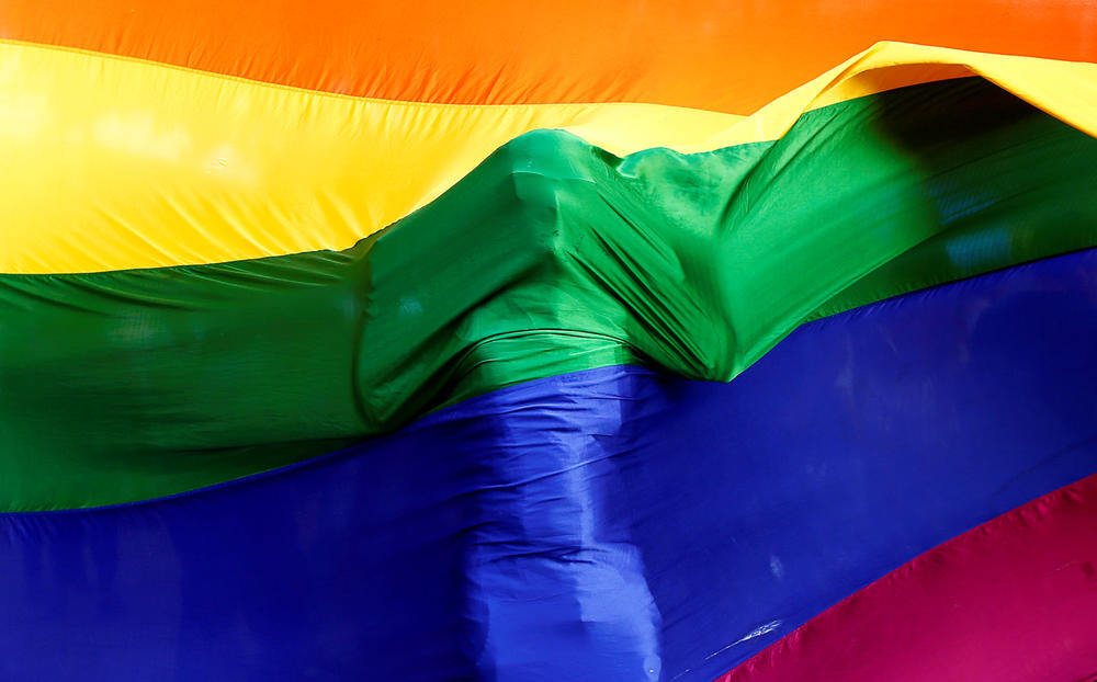 A participant stands behind a rainbow flag during a vigil in Mumbai, India, on June 16, 2016, held in memory of the victims of the Pulse nightclub shooting in Orlando, Fla.
