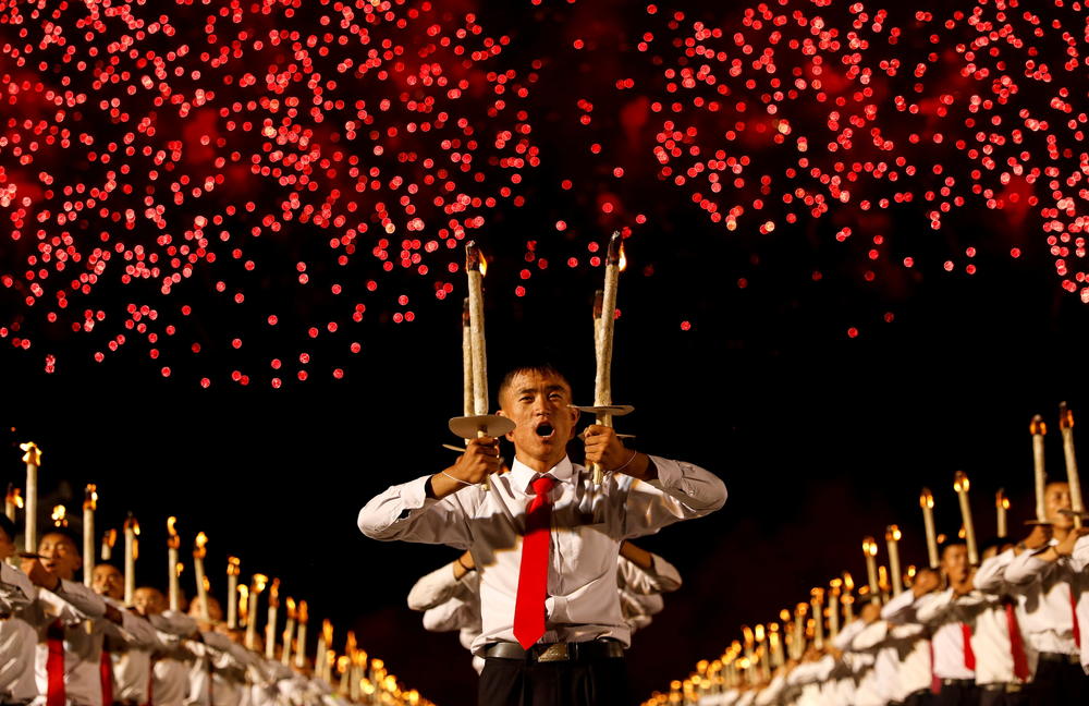 Fireworks explode over participants during a torchlight procession during the celebration marking the 70th anniversary of North Korea's foundation in Pyongyang, North Korea, on Sept. 10, 2018.