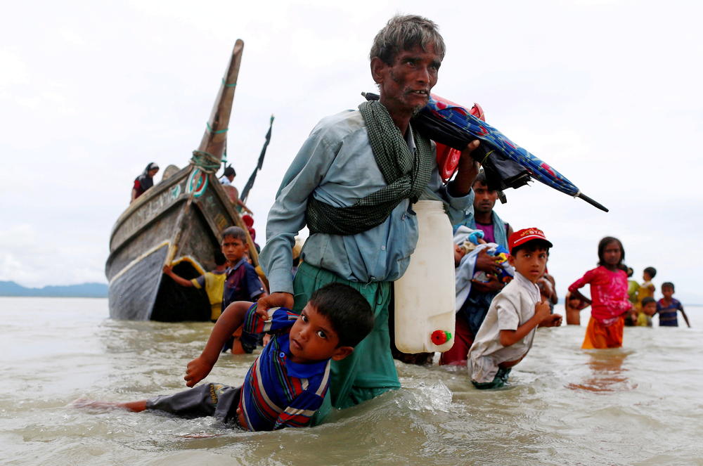 A Rohingya refugee pulls a child as they walk to shore after crossing the Bangladesh-Myanmar border by boat through the Bay of Bengal in Shah Porir Dwip, Bangladesh, on Sept. 10, 2017.