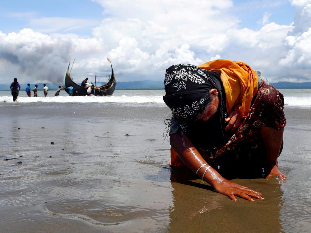 An exhausted Rohingya refugee woman touches the shore after crossing the Bangladesh-Myanmar border by boat through the Bay of Bengal, in Shah Porir Dwip, Bangladesh, on Sept. 11, 2017.