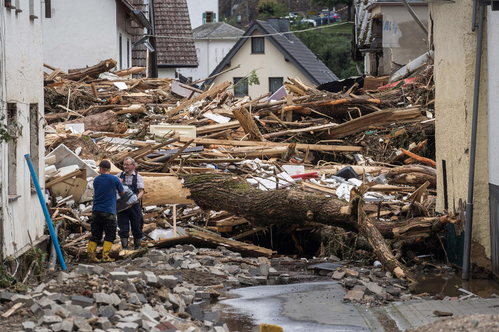 Two men try to secure goods near houses destroyed by floods Thursday in Schuld.