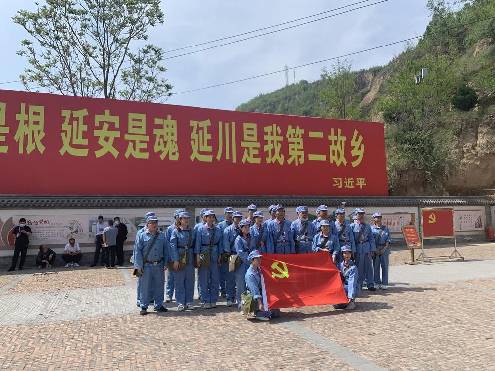 Tourists dressed up as People's Liberation Army soldiers pose in Liangjiahe village, where a teenage Xi Jinping spent seven years doing hard labor. Today the village is a popular red tourism site. The sign displays a quote from Xi: 