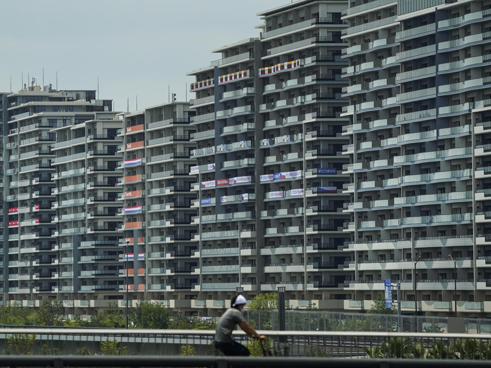 A man rides a bike near the village for the Summer Olympics in Tokyo. On Saturday, officials announced the first case of COVID-19 found at the center housing thousands of athletes.