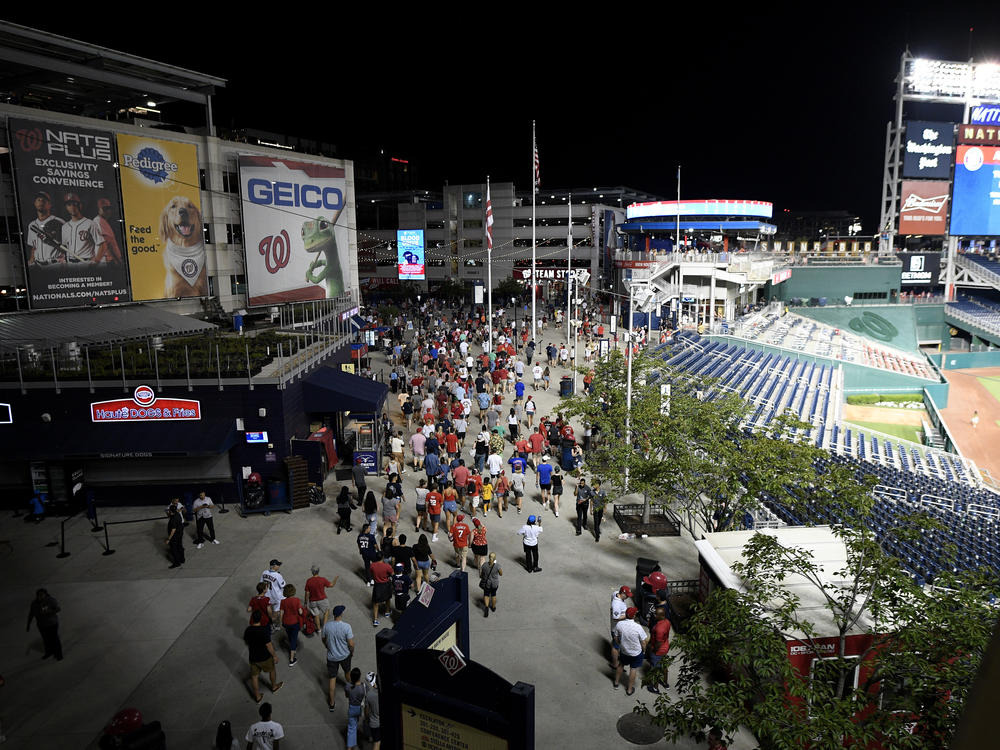 Spectators leave the stadium in the sixth inning of a baseball game between the Washington Nationals and the San Diego Padres on Saturday night in D.C. after a shooting occured outside the park.