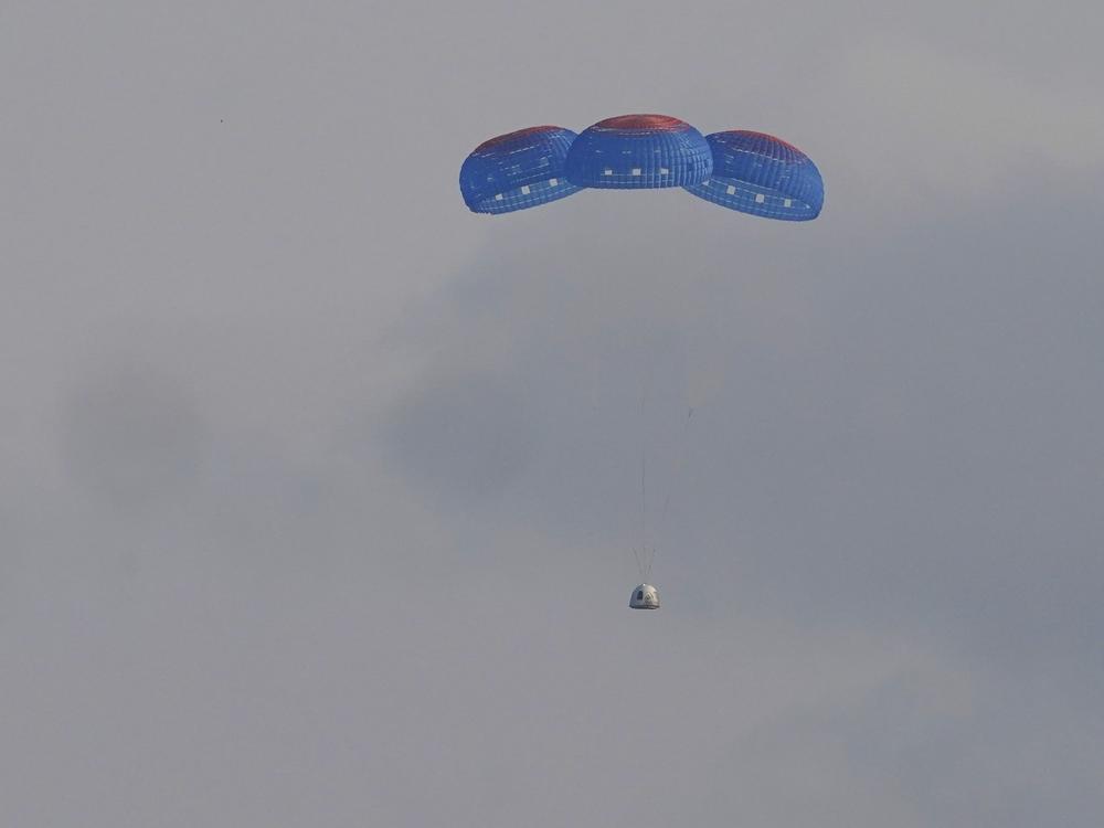 Blue Origin's New Shepard capsule parachutes down to the launch area following its flight into space on Tuesday.