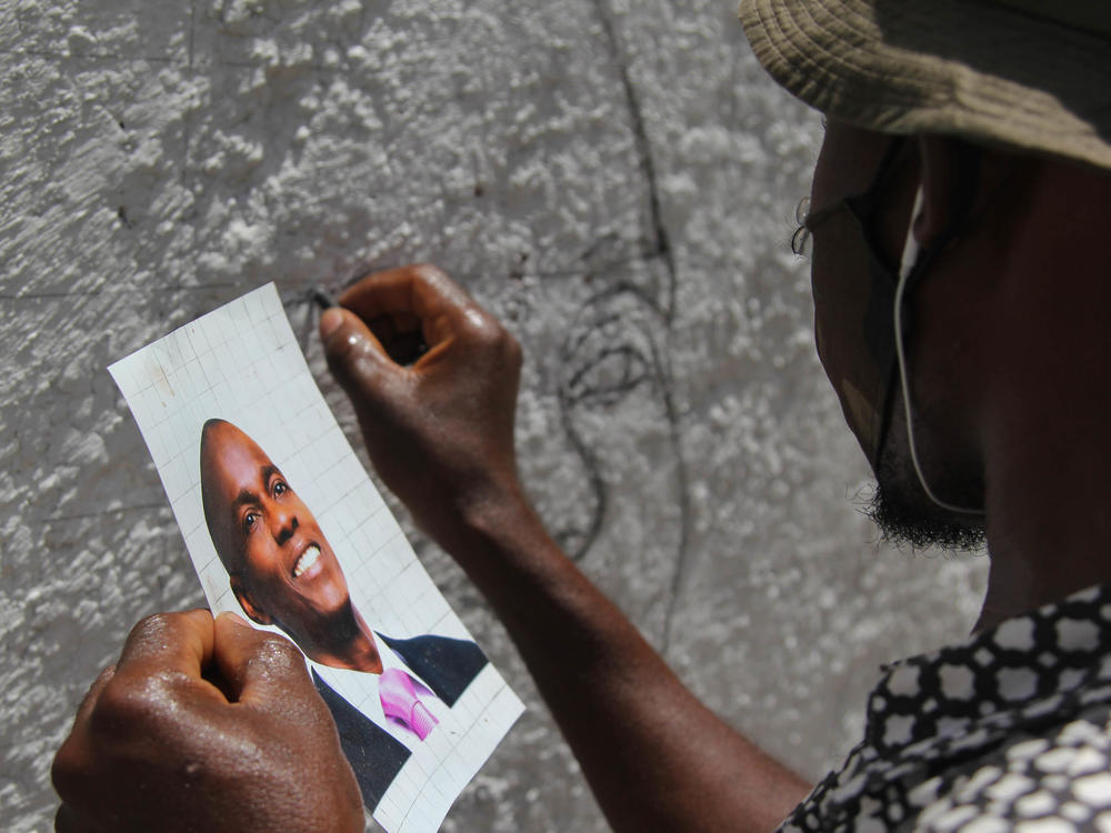 An artist who goes by the name Jamesy Jay paints a mural of slain Haitian president Jovenel Moïse on the road leading to the president's private residence above Port-au-Prince.