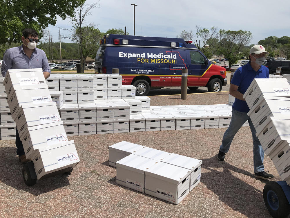 Campaign workers David Woodruff, left, and Jason White, right, deliver boxes of Medicaid expansion initiative signatures to the Missouri secretary of state's office in Jefferson City, Mo. on May 1, 2020.