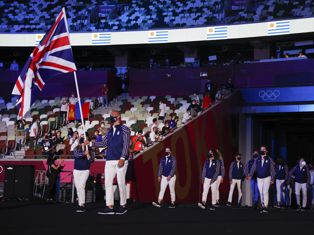 Flag bearers Hannah Mills and Mohamed Sbihi of Team Great Britain lead their team out.