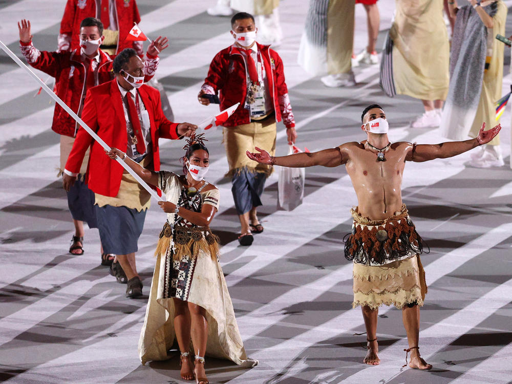 Flag bearers Malia Paseka and Pita Taufatofua of Team Tonga lead their team out.