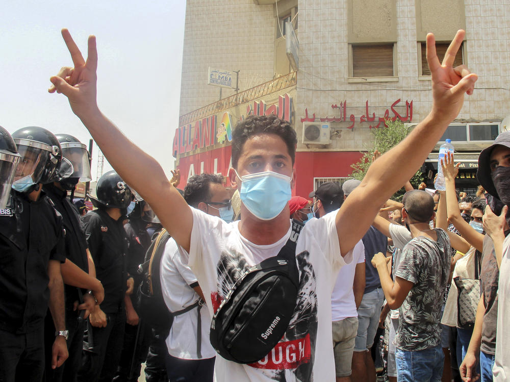 A demonstrator flashes victory signs as he faces Tunisian police officers during a demonstration in Tunis, Tunisia, on Sunday.
