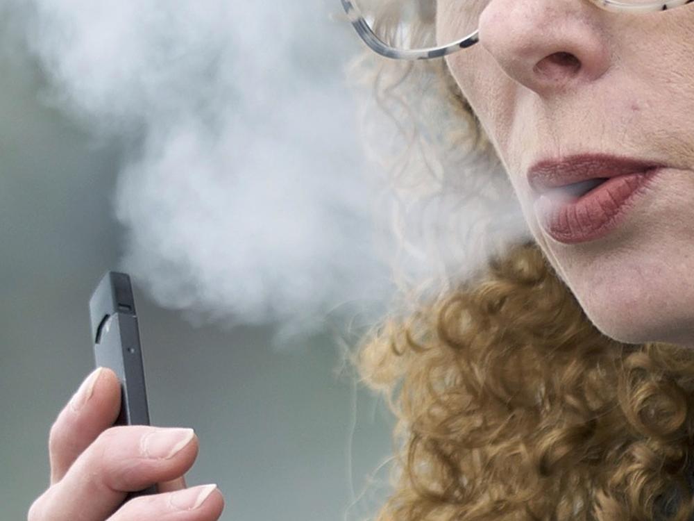 A woman exhales while vaping from a Juul pen e-cigarette in Vancouver, Wash., in 2019. Philip Morris is manufacturing its own type of electronic cigarette. The company does not make Juul pens.