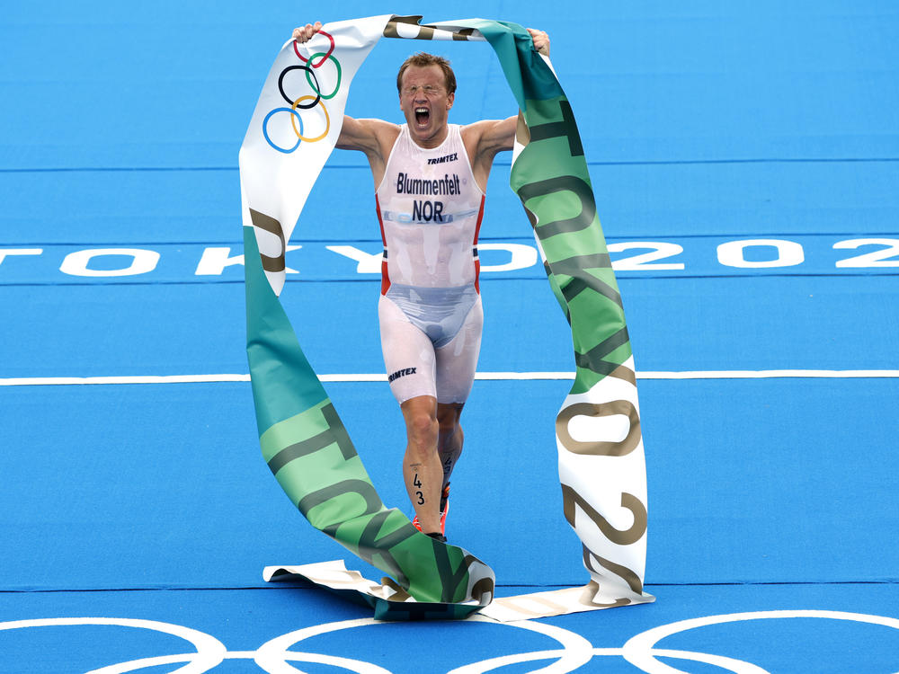 Norway's Kristian Blummenfelt celebrates as he crosses the line Monday to win the men's triathlon at the Tokyo Olympics. Blummenfelt won after a miscommunication between a media boat and the starting officials caused a rare false start in the endurance race.