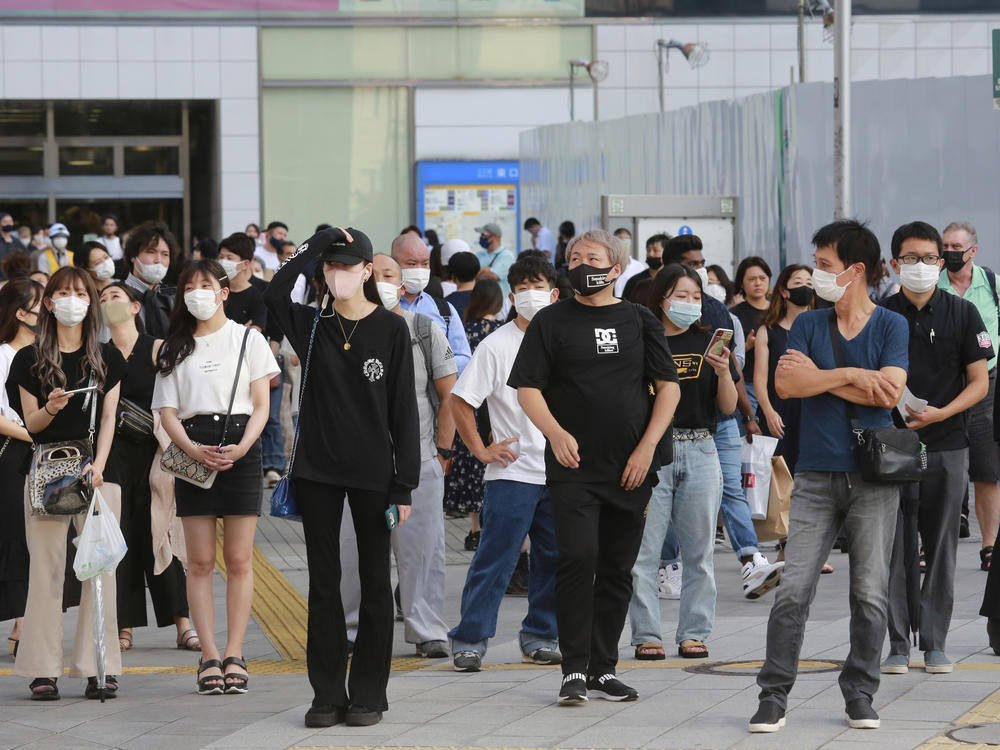 People wearing face masks to protect against the spread of the coronavirus stand at an intersection in Tokyo on Tuesday.