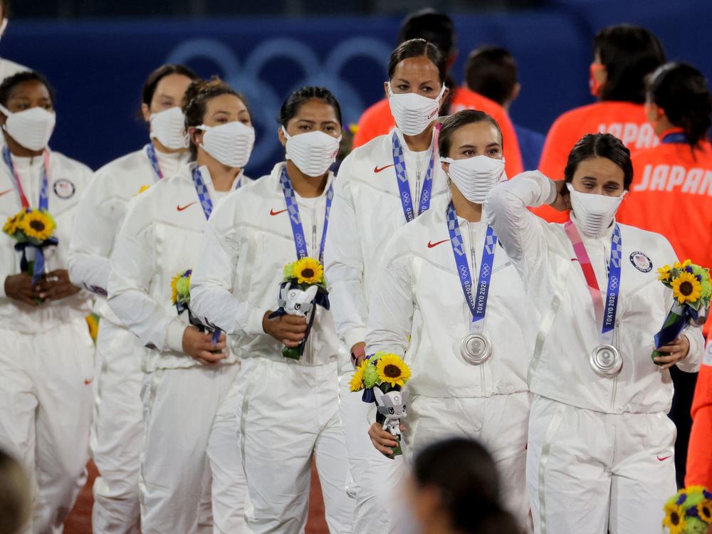 Silver medal winning USA softball team players walk with their medals on the podium during the medal ceremony for the softball competition in the Tokyo 2020 Olympic Games.