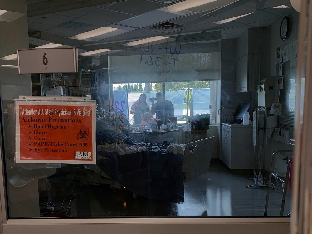 Family members gather outside the window of a COVID-19 patient at Lake Regional Hospital in Osage Beach, Mo., on Monday.