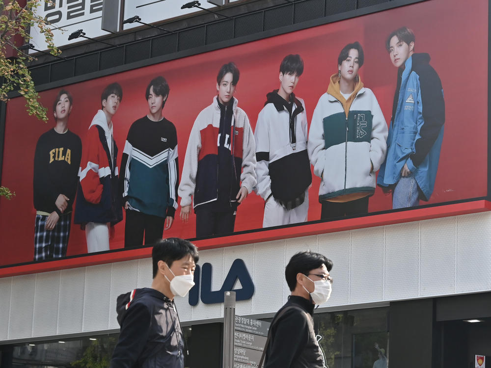 People walk past a poster showing members of the K-pop group BTS in Seoul on October 12, 2020. It's one of the most popular bands in the world, with an extremely devoted fan base.