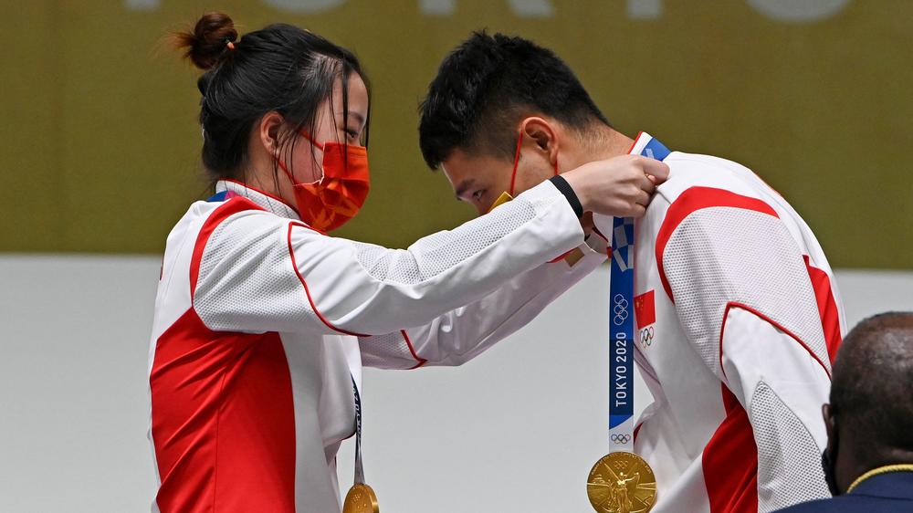 China's Yang Qian (left) and Yang Haoran put gold medals on each other during the 10 meter air rifle mixed team medal ceremony at the Asaka Shooting Range in Tokyo on Tuesday.
