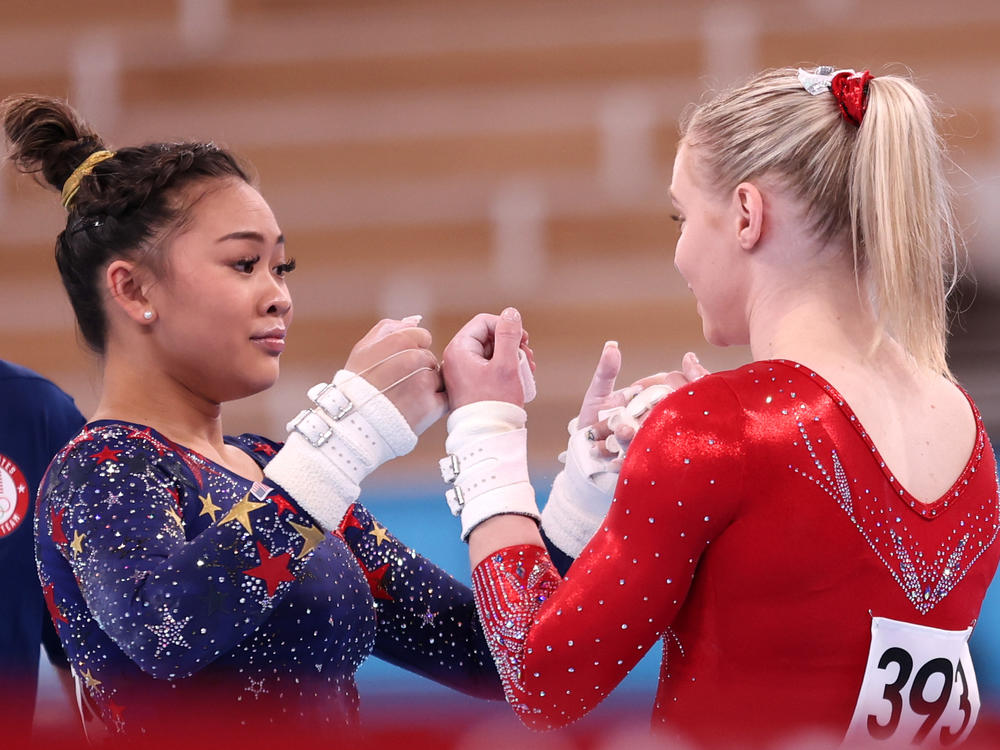 U.S. gymnasts Sunisa Lee and Jade Carey fist-bump during gymnastics qualifiers on Sunday at the Tokyo Olympics.