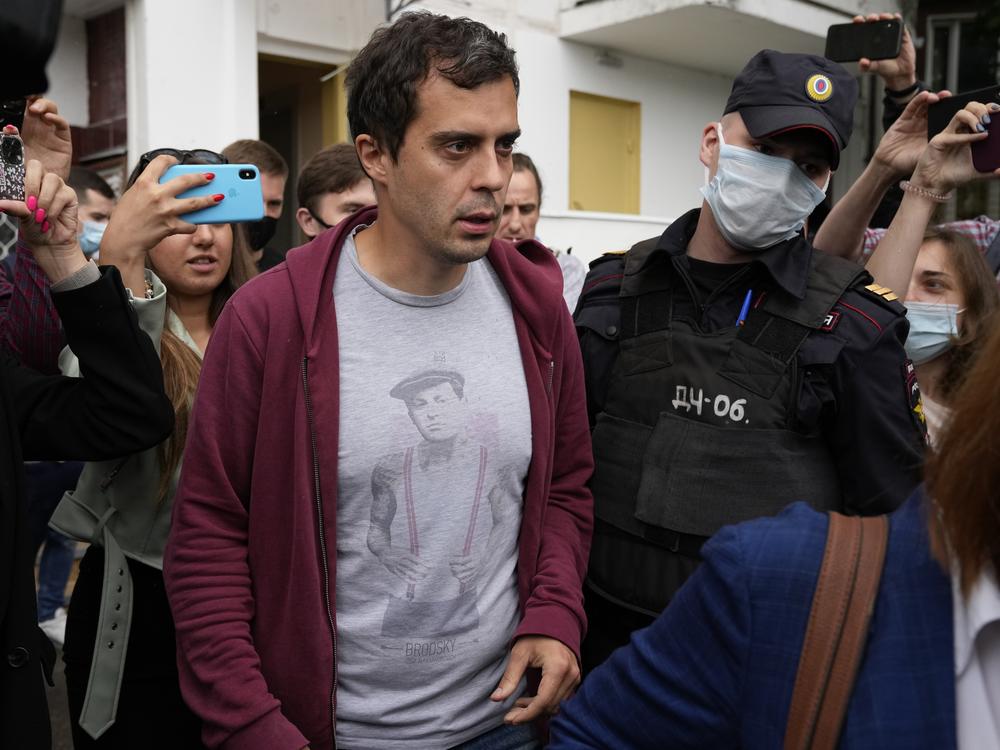 Roman Dobrokhotov, chief editor of <em>The Insider,</em> walks surrounded by police and journalists, in Moscow on Wednesday. Police raided his home after the<em> </em>investigative news organization was designated as a 