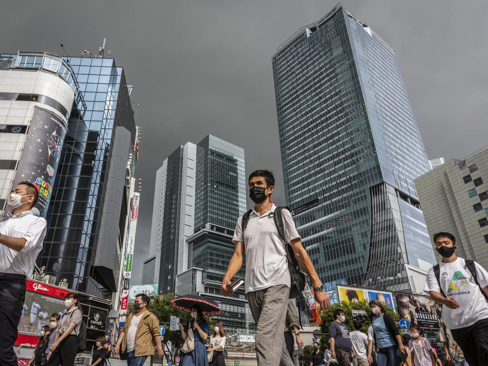 People wearing face masks cross Shibuya crossing on July 30, 2021 in Tokyo, Japan. Tokyo has seen day-on-day record increases in COVID-19 infection rates over the last three days causing concern amongst officials in Tokyo.
