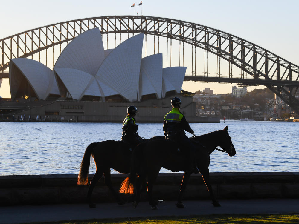 Mounted police officers patrol around the edge of Sydney Harbor on Friday as the Australian city has been locked down amid a new surge in coronavirus infections.
