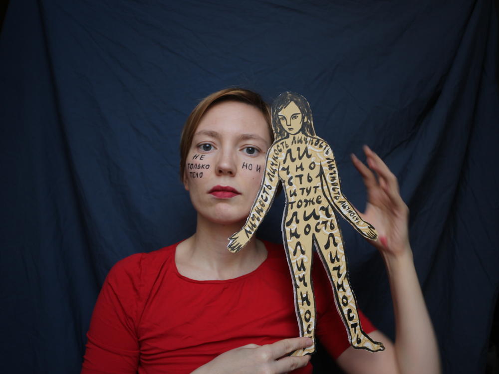 A self-portrait of Darya Apakhonchich, with the writing on her face and a figure of a woman saying: 