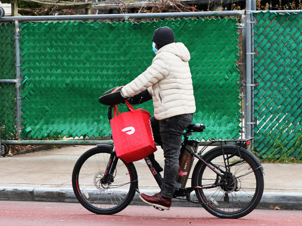 A DoorDash delivery person rides their bike in New York City. Workers across the country went on strike on July 31 to demand higher pay and tip transparency.