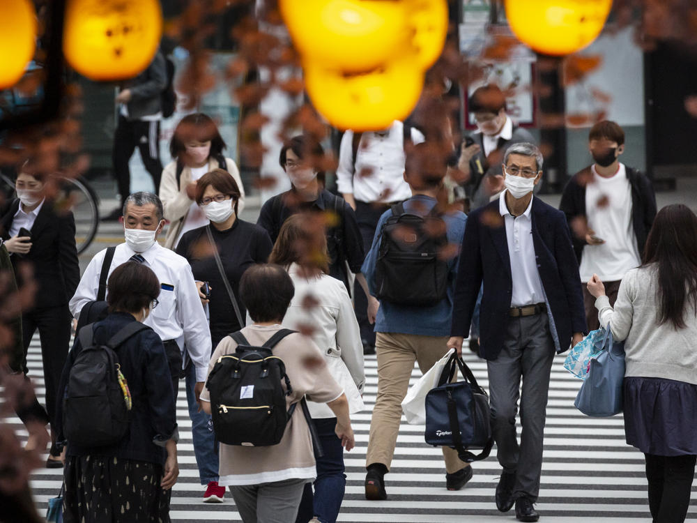 People in Tokyo wear masks on May 7. Daily coronavirus infections in Japan's capital have topped 4,000 — nearly four times as many as a week ago.