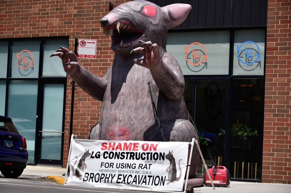 An inflatable Scabby the Rat outside of LG Construction in Chicago. The banner in front of the rat shows the union is shaming the construction company for doing business with Brophy Excavation.