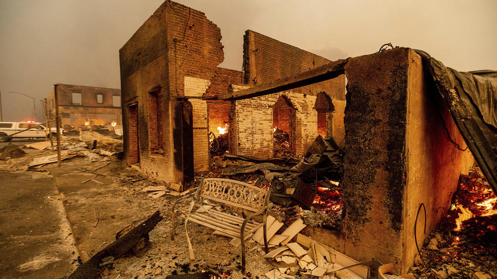 A bench stands outside a scorched building as the Dixie Fire tears through the Greenville community of Plumas County, Calif., on Aug. 4, 2021.