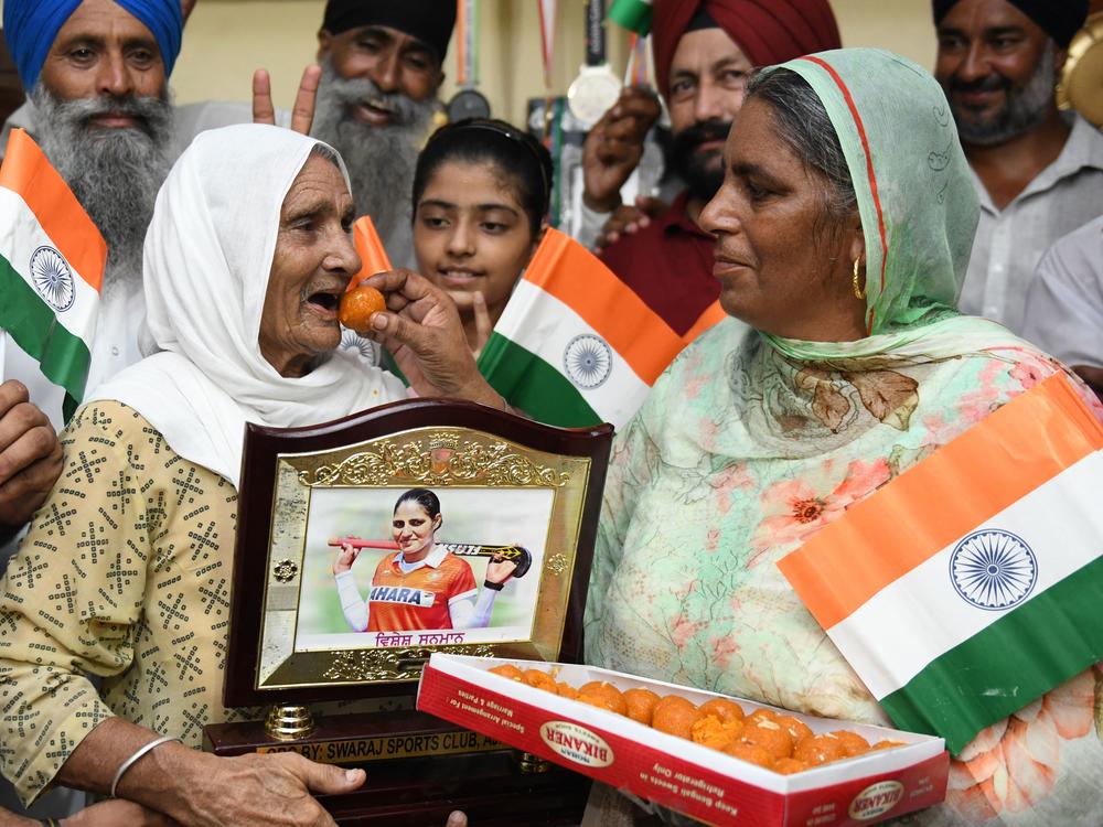 The mother of Indian hockey player Gurjit Kaur offers sweets to her mother-in-law as they celebrate in their village of Miyadi Kalan, after Gurjit Kaur's team won the women's quarterfinal match at the Tokyo Olympics.