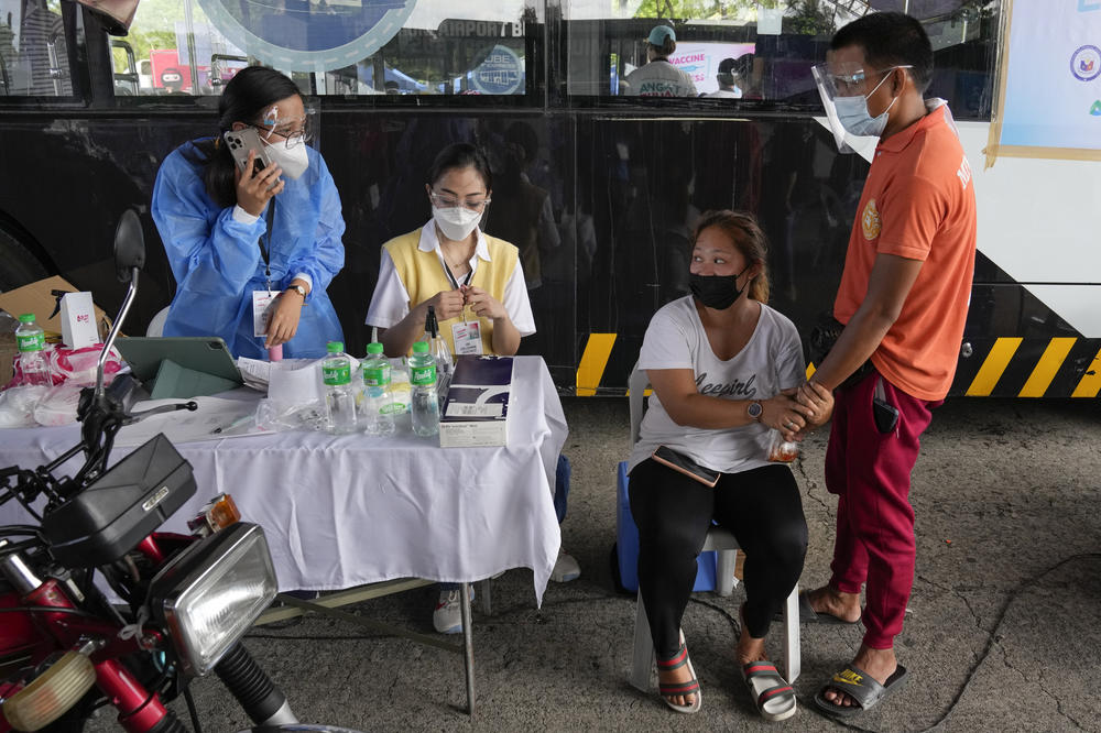 A woman holds the hands of her husband as they wait for a shot of the Sinovac COVID-19 vaccine at a drive-through vaccination center in Manila, Philippines, on June 22. Doubts have spread among Filipinos about the Chinese-made vaccine.