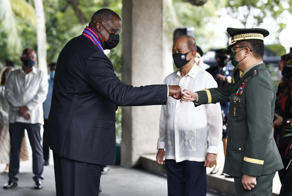 U.S. Defense Secretary Lloyd Austin (left) greets the chief of staff of the Armed Forces of the Philippines, Gen. Cirilito Sobejana (right), with a fist bump as Philippine Defense Secretary Delfin Lorenzana looks on at Camp Aguinaldo on July 30.