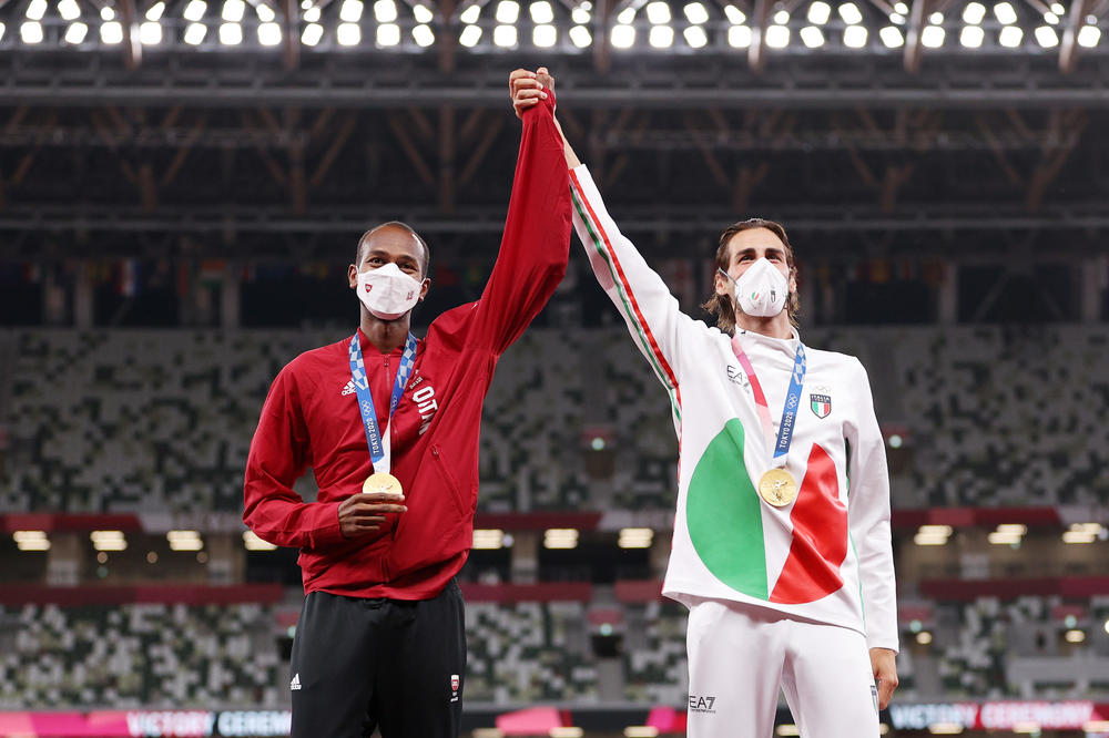 Joint gold medalists Mutaz Essa Barshim of Team Qatar and Gianmarco Tamberi of Team Italy celebrate on the podium during the medal ceremony for the men's high jump at the Tokyo Olympics.